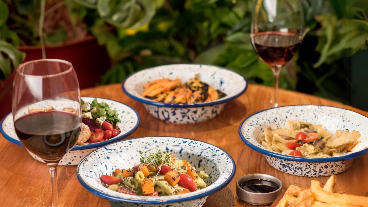 Mesa de Nipoti con platos de pasta, ensalada y copas de vino